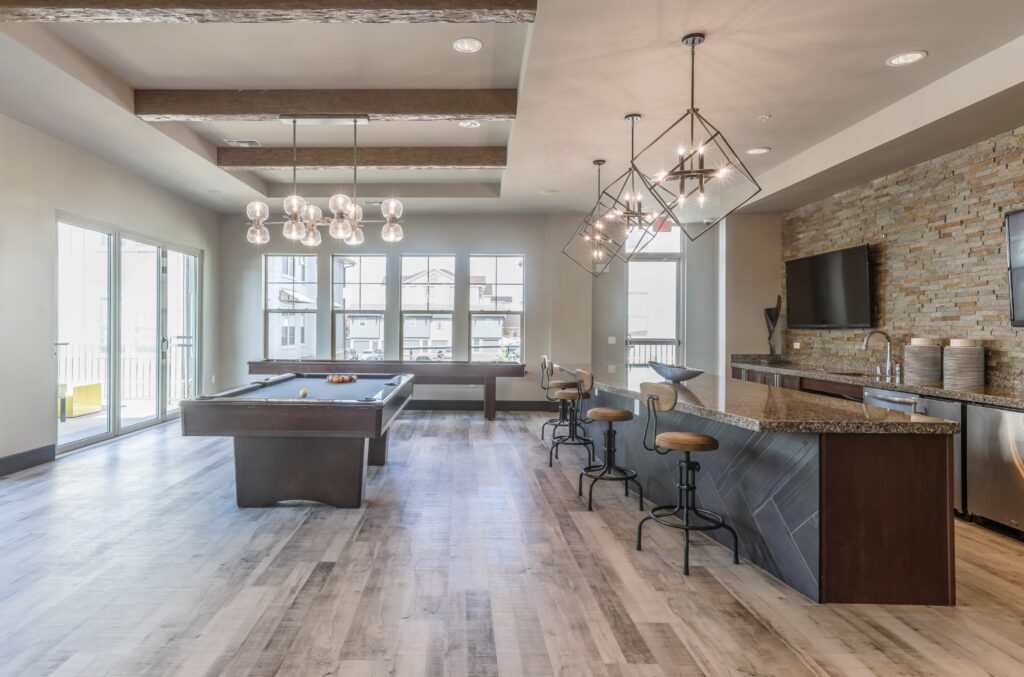 Clubhouse lounge with billiards table and patio seating, kitchen and TVs